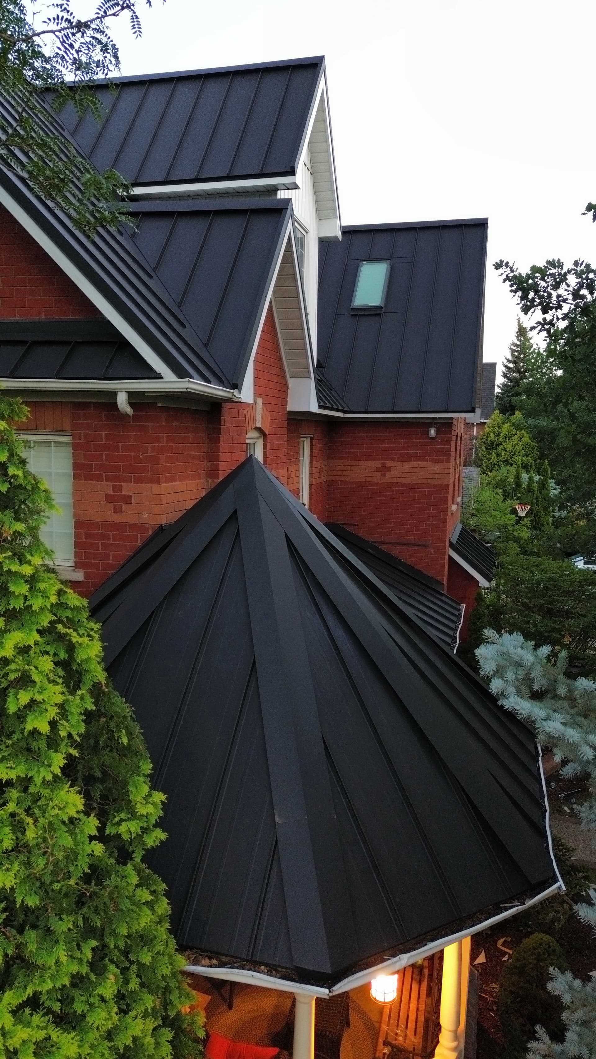 Aerial view of matte black standing seam fan-hip roof — VAH Construction