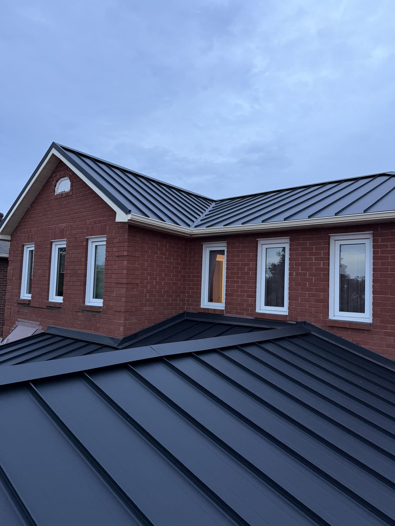Charcoal standing seam roof on red brick home — VAH Construction