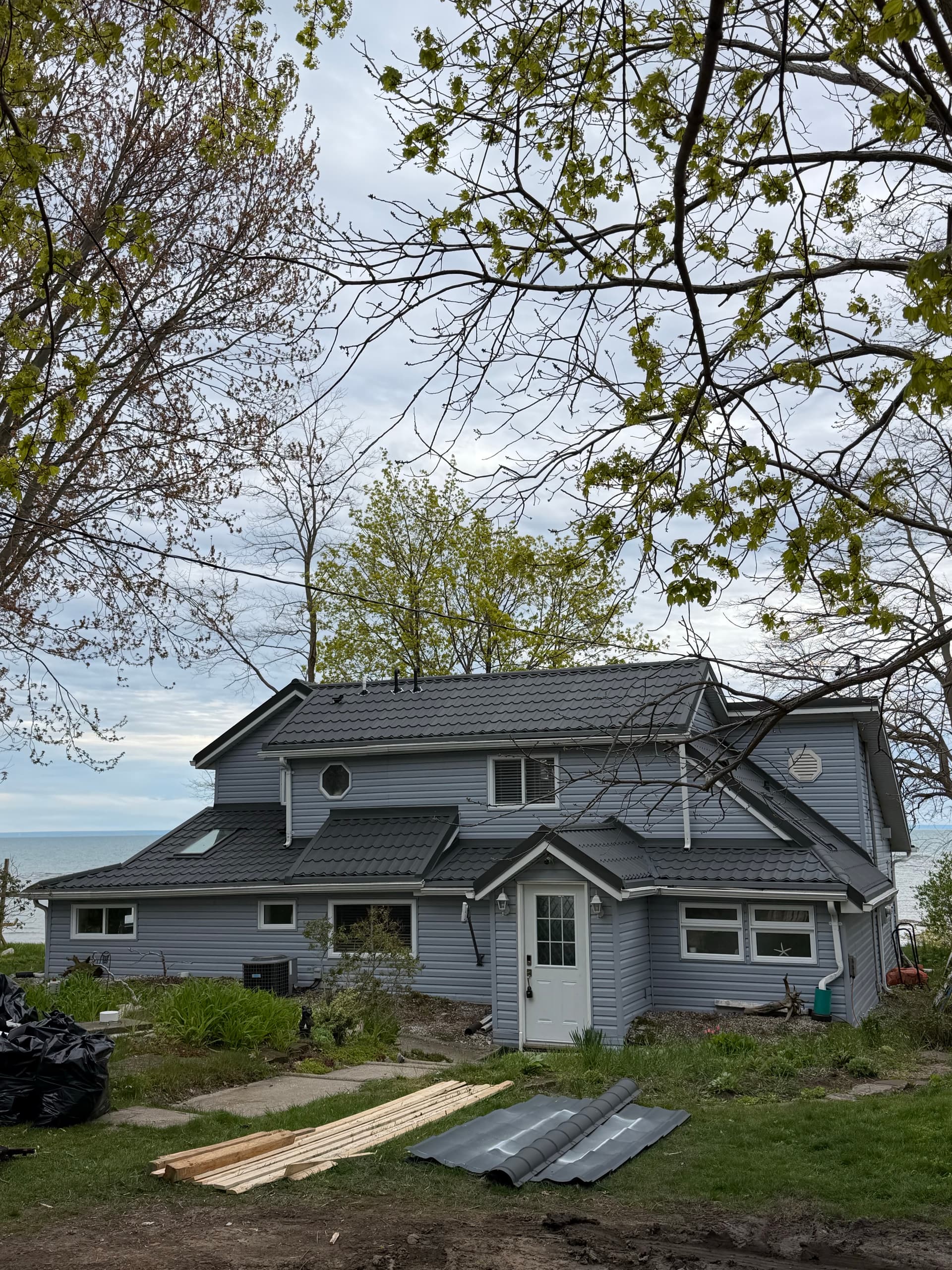 Lakefront home with dark grey metal tile roof — VAH Construction
