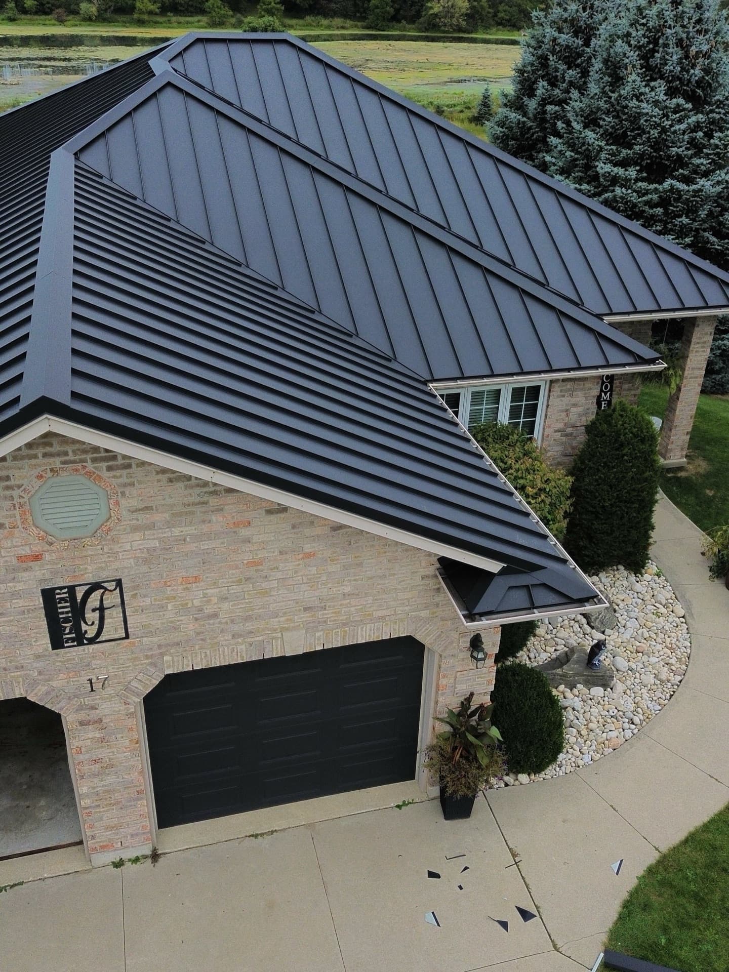 Black standing seam roof on a brick bungalow with attached garage — VAH Construction