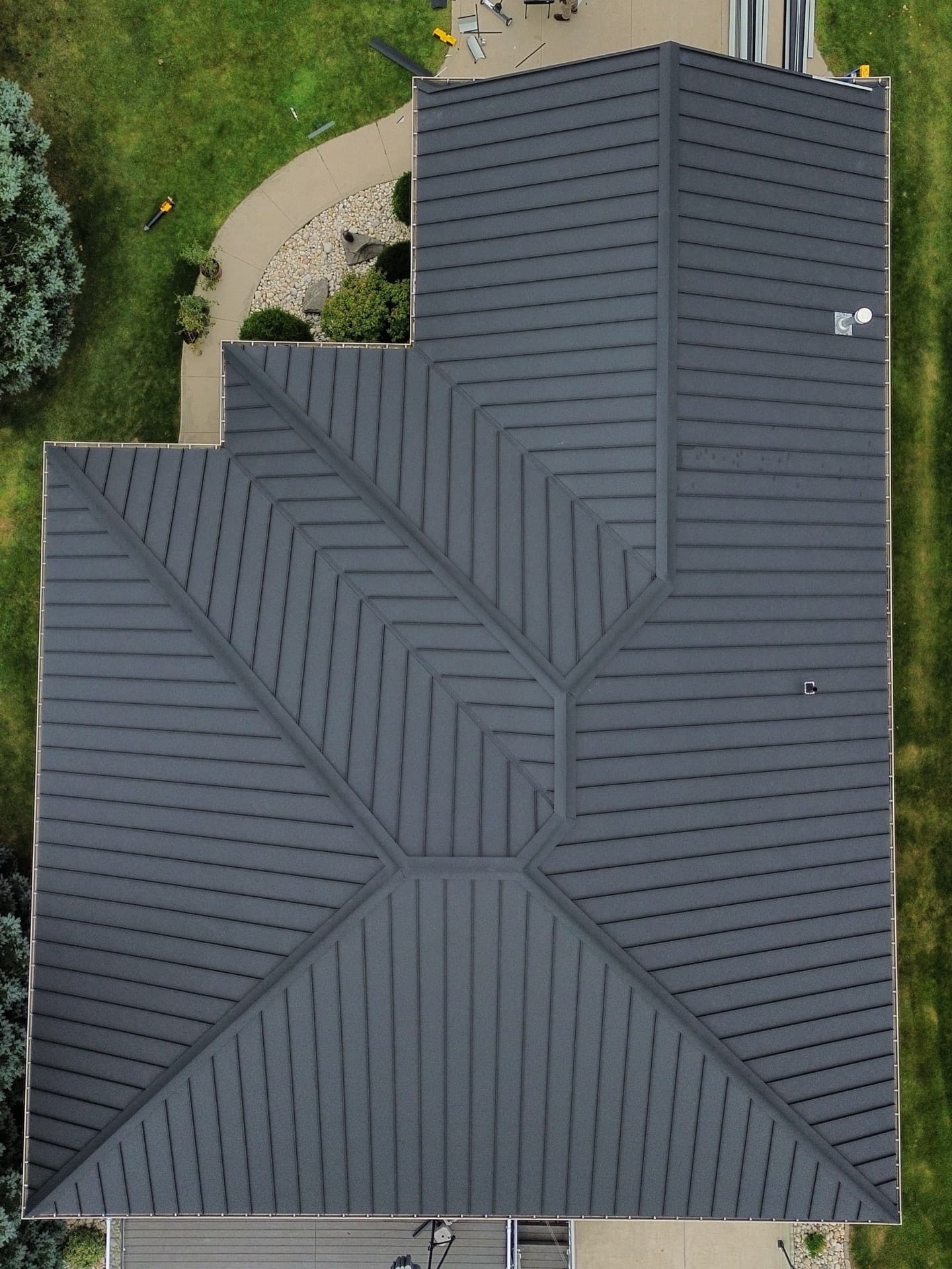 Top-down aerial view of a black standing seam multi-hip roof — VAH Construction